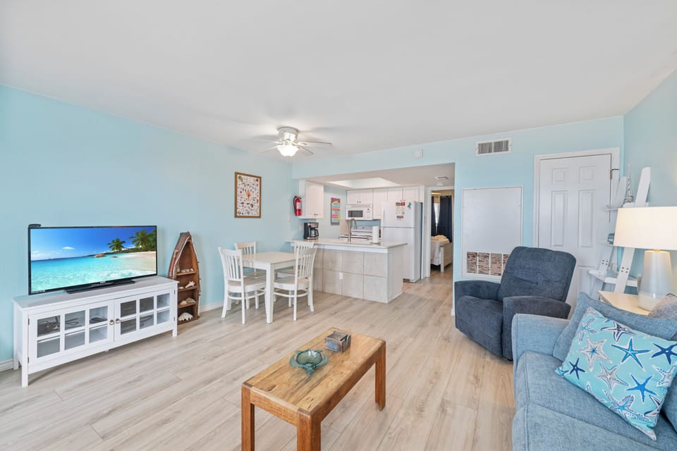 Relax in your bright open-concept space with modern kitchen, comfortable seating, and large TV for cozy evenings.