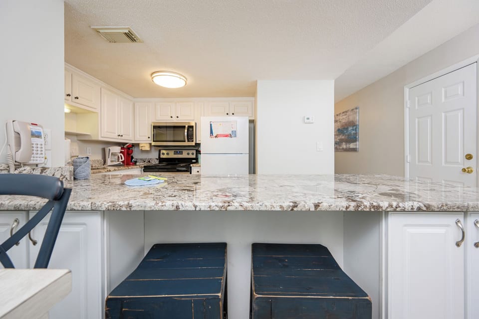 Enjoy casual conversations at the cozy bar seating while preparing snacks in this inviting kitchen space