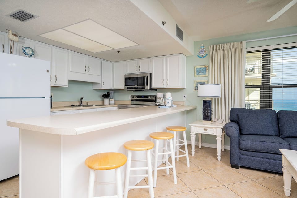 Inviting kitchen with white cabinetry,white and stainless appliances, and bar seating for a cozy dining experience