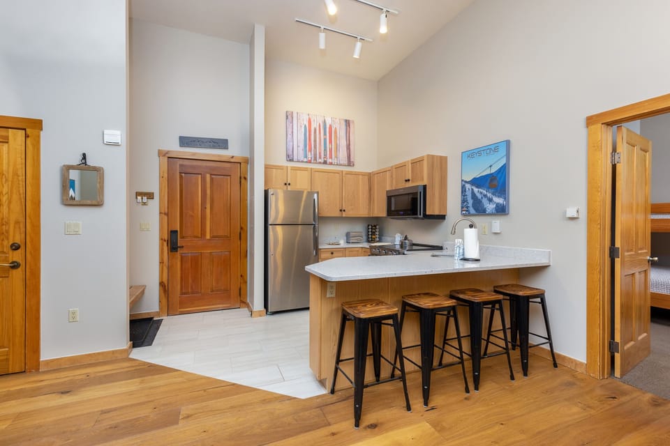 Your modern kitchen awaits with sleek appliances, breakfast bar seating, and warm wood finishes creating the perfect space for morning coffee or evening meals.