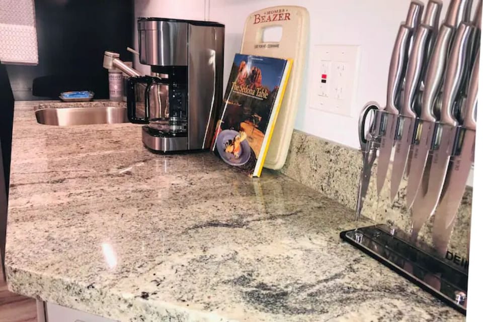 Granite countertops with coffee maker, Sedona cookbook, and modern knife set.