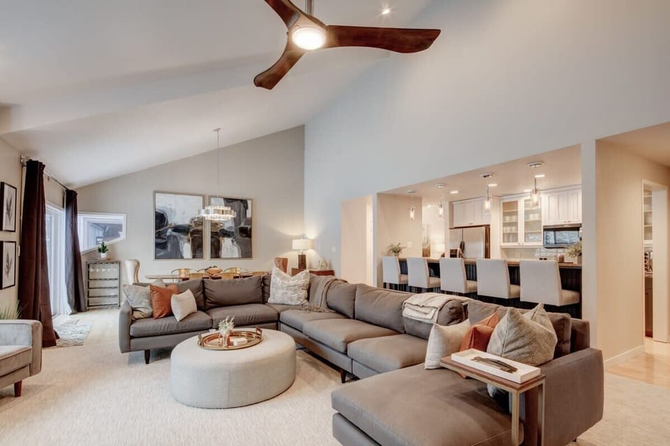 Great room - open kitchen with breakfast bar seating on the right, dining area behind the sofa