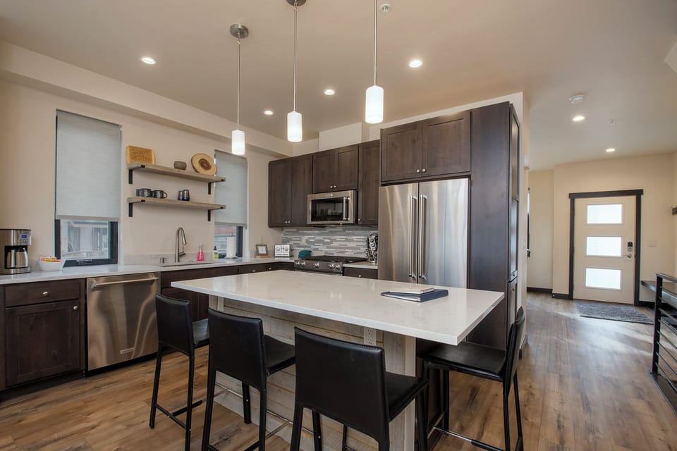Your gourmet kitchen features sleek dark cabinets, stainless steel appliances, and a spacious island perfect for morning coffee or evening conversations.