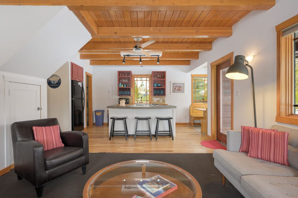Relax in your open-concept living space with exposed wood beams, modern kitchen, and cozy seating perfect for gathering.