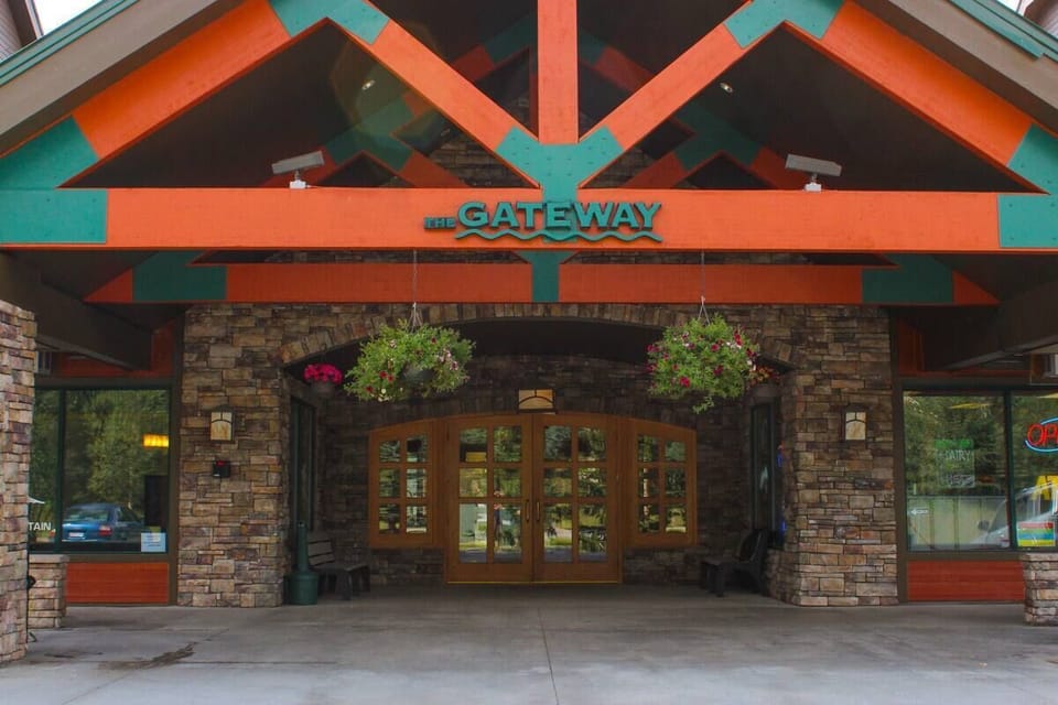 Front entrance of The Gateway building with stone walls, wooden beams, hanging flower baskets, and glass doors. "The Gateway" sign is prominently displayed above the entrance.