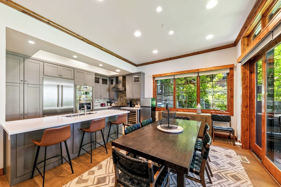 Your gourmet kitchen invites culinary adventures with sleek appliances, spacious seating, and lake views through warm wood-framed windows.