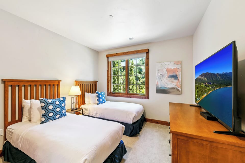 Rest peacefully in your twin bedroom with warm wood accents, crisp linens, and modern amenities for your mountain getaway.