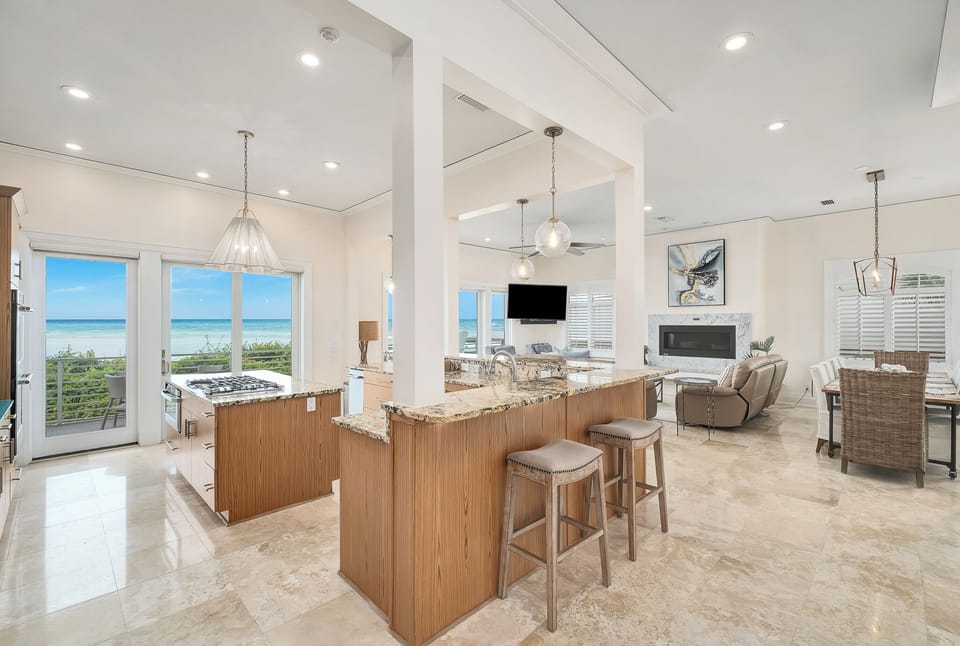 You'll love the open layout connecting your gourmet kitchen, dining, and living areas—all framed by stunning ocean views through expansive windows that bring the beachfront right inside.