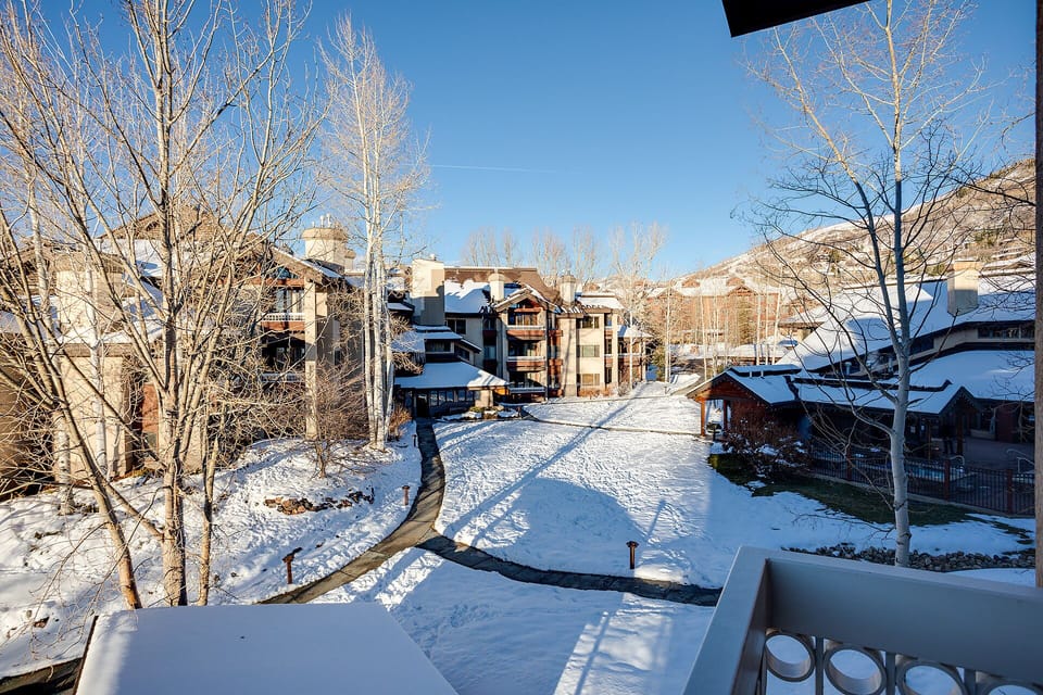 Scenic winter balcony overlooks snow-covered mountain village with cozy ski lodges and pristine alpine surroundings.