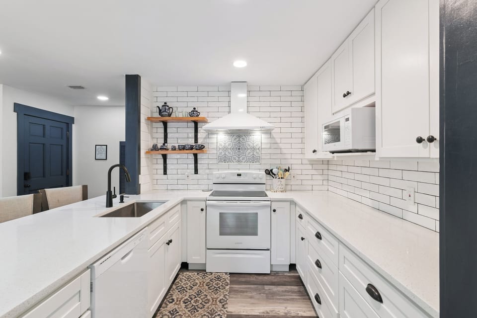 Step into your fully equipped kitchen with white subway tile backsplash, modern appliances, and open shelving—perfect for preparing homemade meals in style.