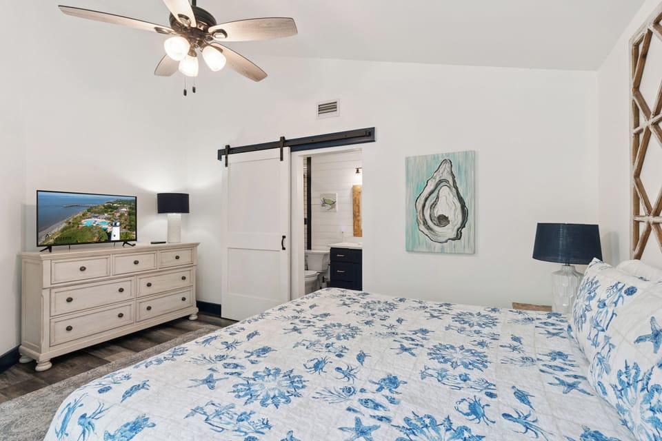Unwind in your serene coastal retreat with breezy ceiling fans, charming barn-door accents, and artwork that echoes the sea. Your private sanctuary awaits with modern comforts and seaside style.