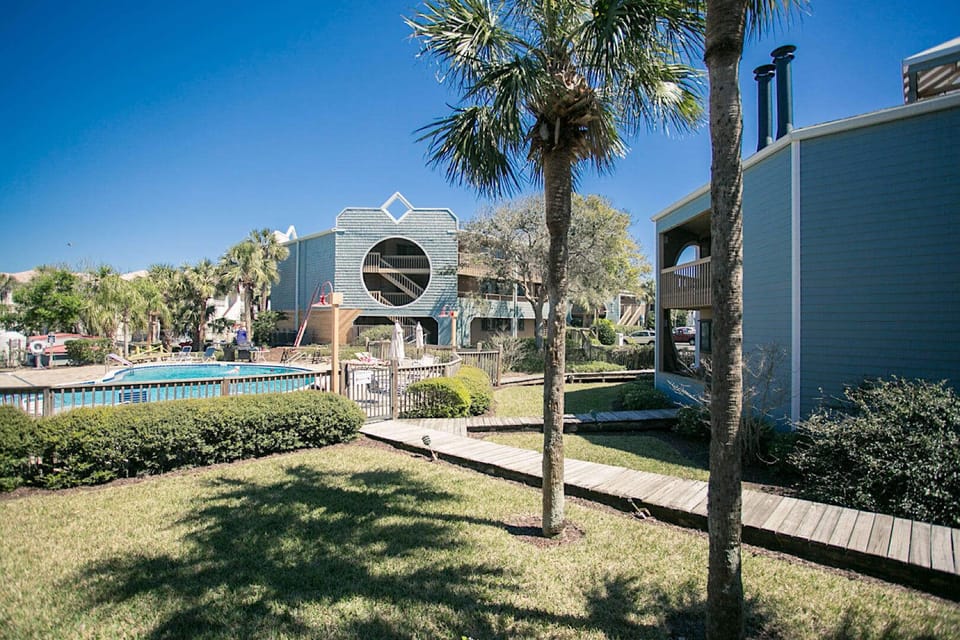 Resort walkway winds past palm trees and manicured lawns to the poolside.