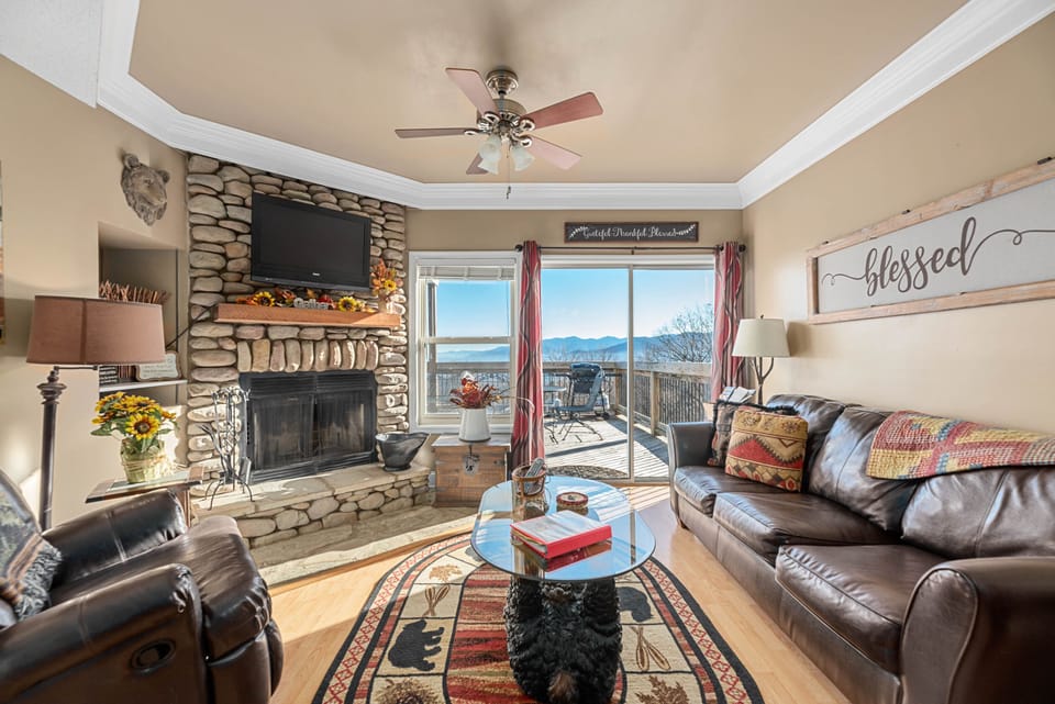 Living room with stone fireplace and floor-to-ceiling mountain views