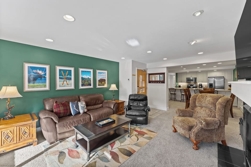 Relax in your spacious living room featuring plush leather seating, rustic décor, and an open kitchen—perfect for unwinding after mountain adventures.