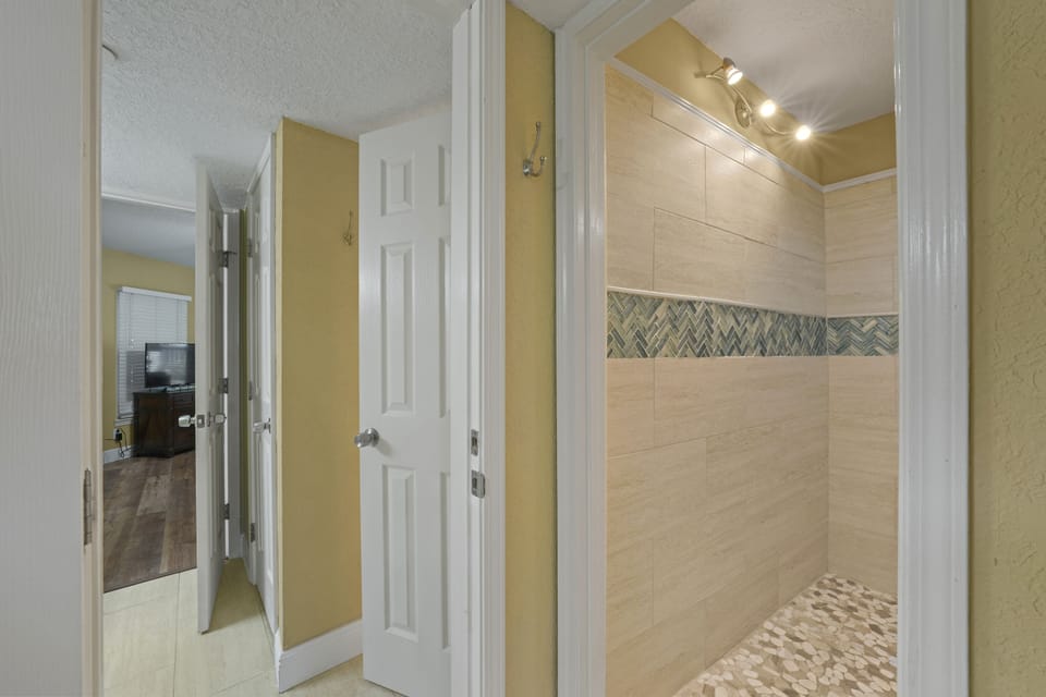 Stylish guest shower with designer tile, pebble-style flooring, and bright lighting for a spa-like experience.