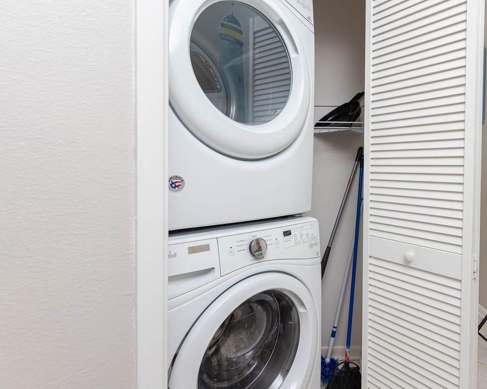 Stacked washer and dryer provide convenient laundry access, complemented by storage space for cleaning supplies