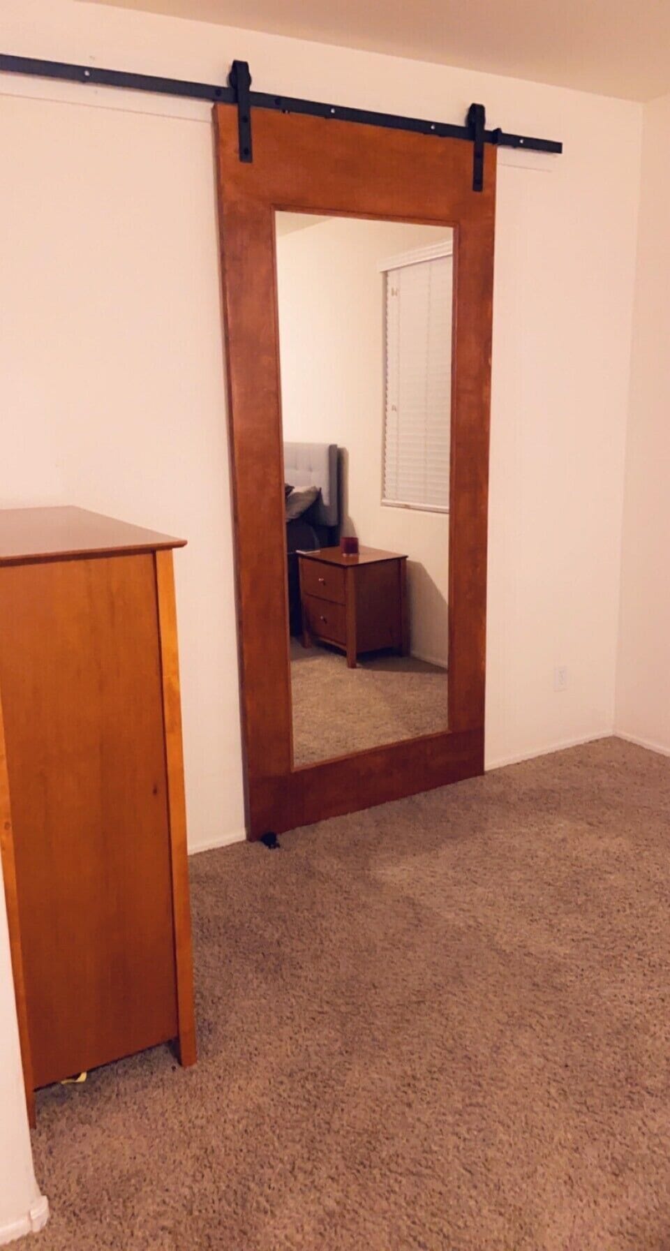 Sliding barn door with mirror separates master bedroom from master bathroom