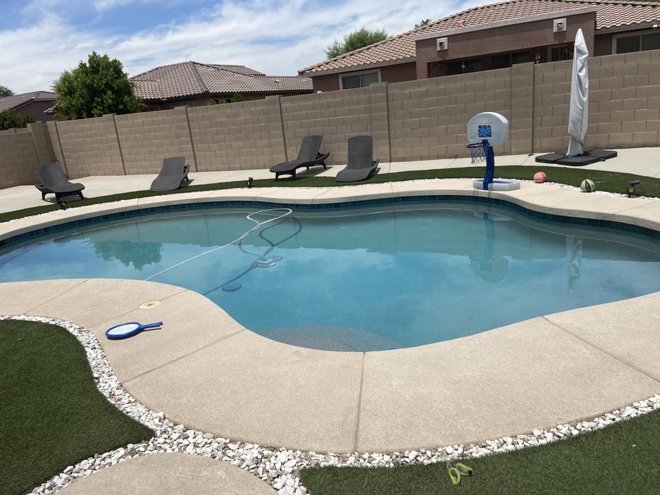 Pool with lounge chairs, basket ball hoop, large umbrella to protect from sun