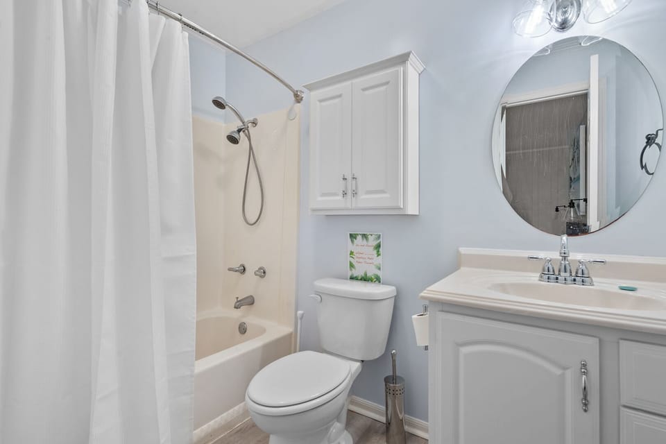Bathroom with a round mirror, vanity and curtained shower at Sun Villas A1 in North Myrtle Beach