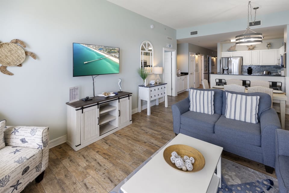 Relax in your bright coastal-themed living room with nautical touches, comfortable seating, and modern entertainment for your perfect beach getaway.