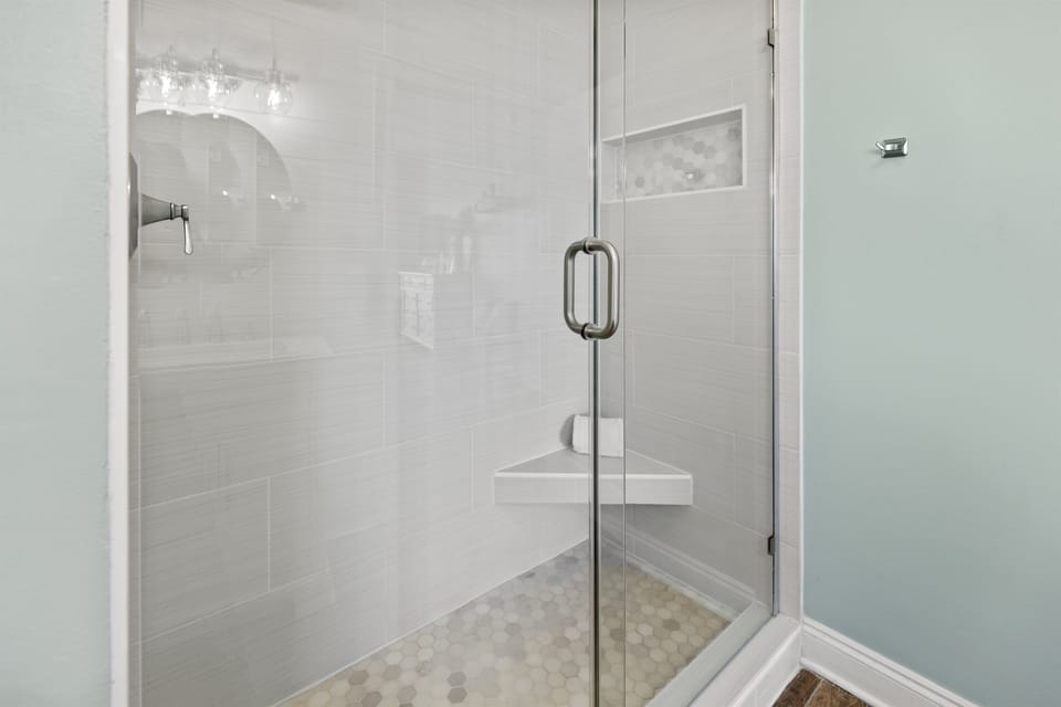 Step into your private glass-enclosed shower with elegant tile work and built-in seating for ultimate relaxation.