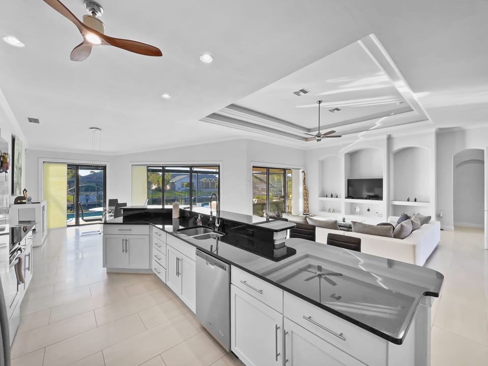 Kitchen with large dark granite island, sink, and white cabinetry