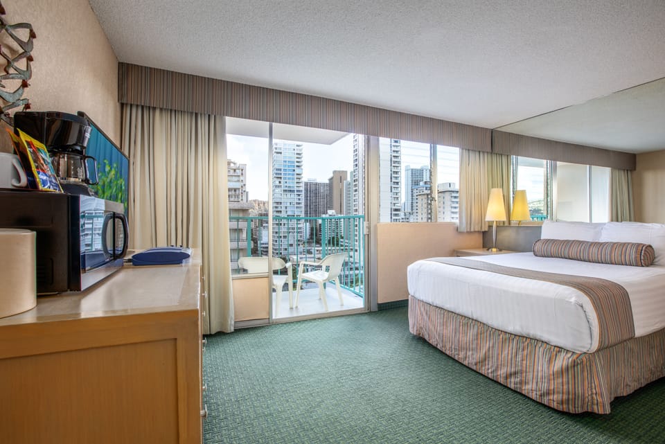 Wake to city skyline views through floor-to-ceiling windows. Your cozy bed, private balcony, coffee maker, and all the comforts of home await in this bright urban retreat.