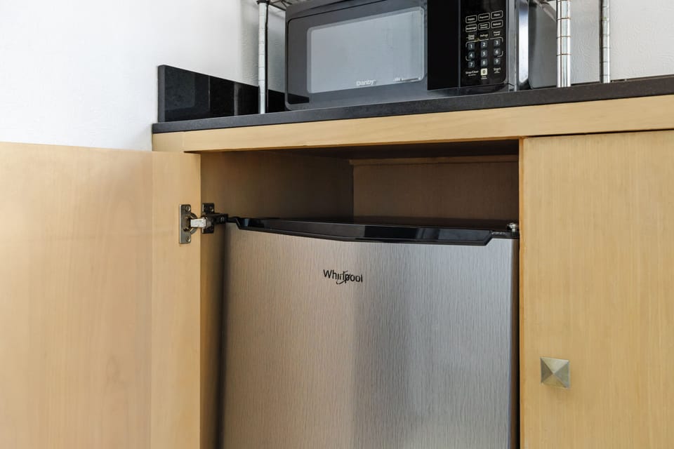 Your kitchenette is equipped with everything you need for convenience—microwave above, a mini fridge below, and ample cabinet space to keep your snacks and essentials organized during your stay.