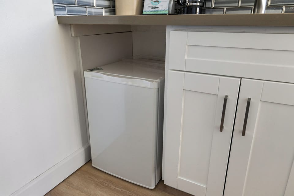 Your kitchen features modern white cabinetry with a convenient under-counter refrigerator, perfect for storing snacks and beverages during your stay.
