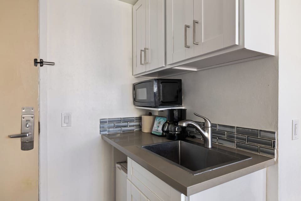 Prepare your morning coffee in this convenient kitchenette, complete with modern appliances and stylish subway tile backsplash for all your culinary needs.