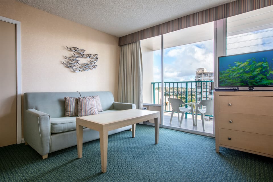 Relax on your private balcony with ocean views, or unwind indoors in your cozy living space with coastal décor and modern comforts like a flat-screen TV.