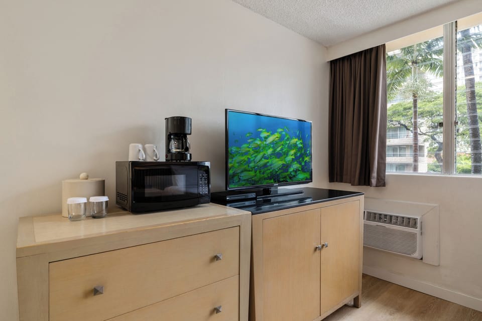 Your modern entertainment setup features a flat-screen TV, microwave, and coffee maker, all perfectly arranged for your comfort.