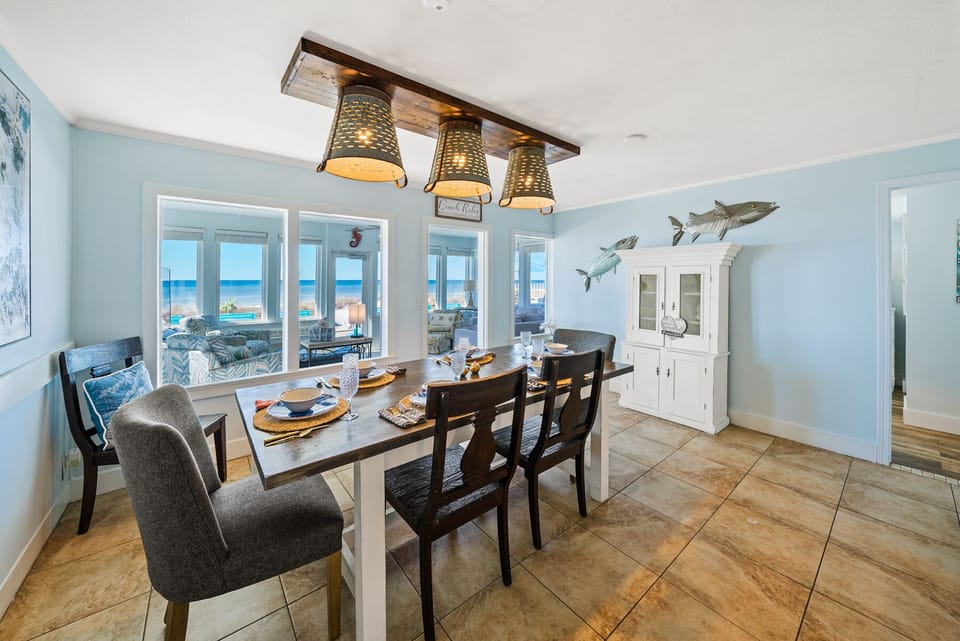 Gather around your coastal dining table where ocean views frame every meal through floor-to-ceiling windows.