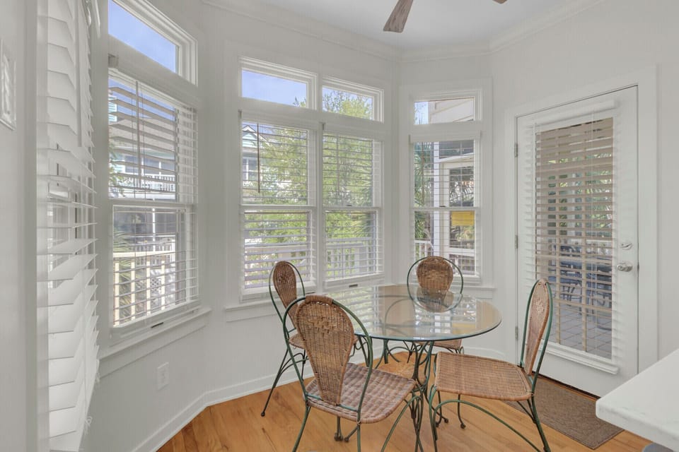 Enjoy your morning coffee in this bright sunroom with wicker seating and plantation shutters filtering soft natural light.