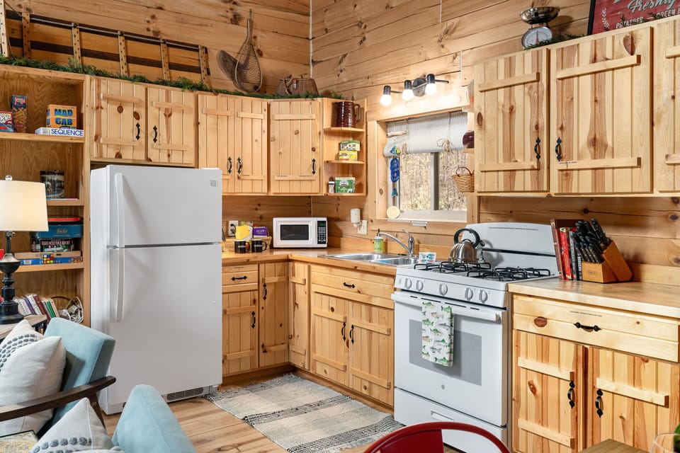 Cabin kitchen with a gas stove/oven, and plenty of cooking utensils.