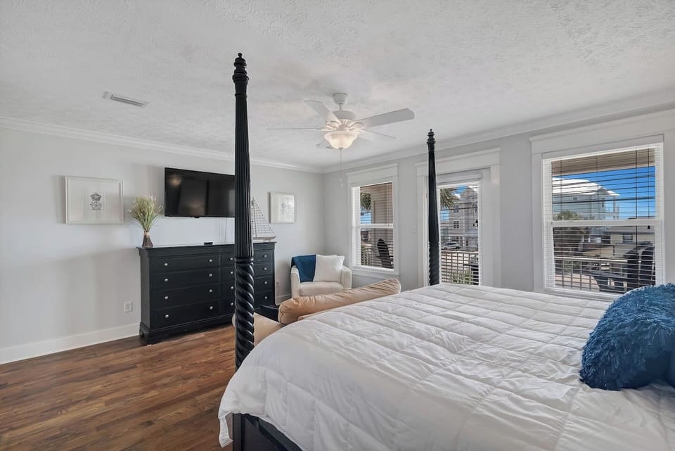 The bedroom has a ceiling fan, mounted smart TV, large closet, and tabletop fan.