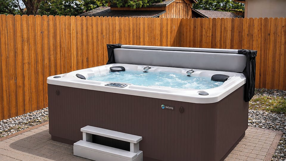 Private, bubbling spa on patio—jets, headrests, and privacy fence.