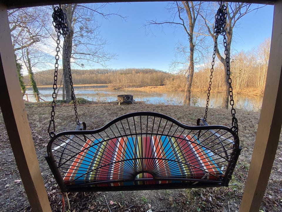 Porch swing below facing river with fire pit 