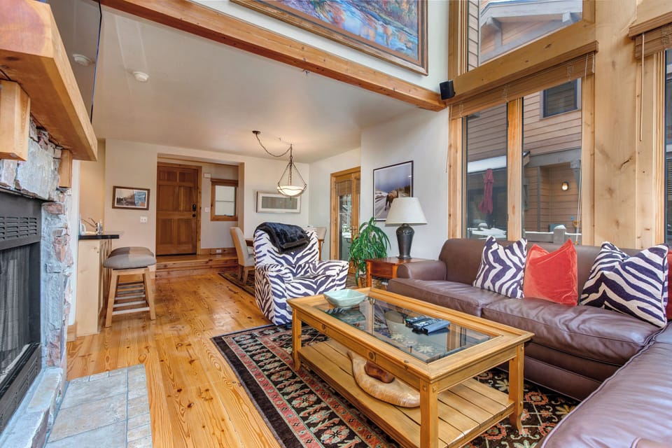 Living Room with vaulted ceilings, stunning windows that allow for an abundance of natural light, leather furnishings, full sofa-bed, gas fireplace, and 55" Vizio TV