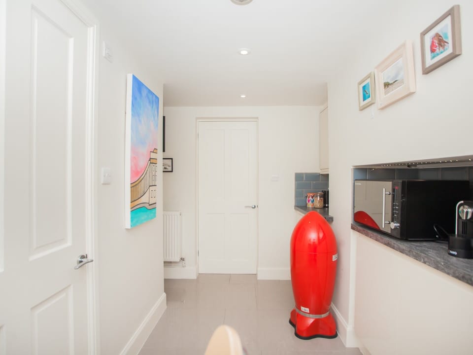 Kitchen with microwave, coffee machine, electric hob and fridge.