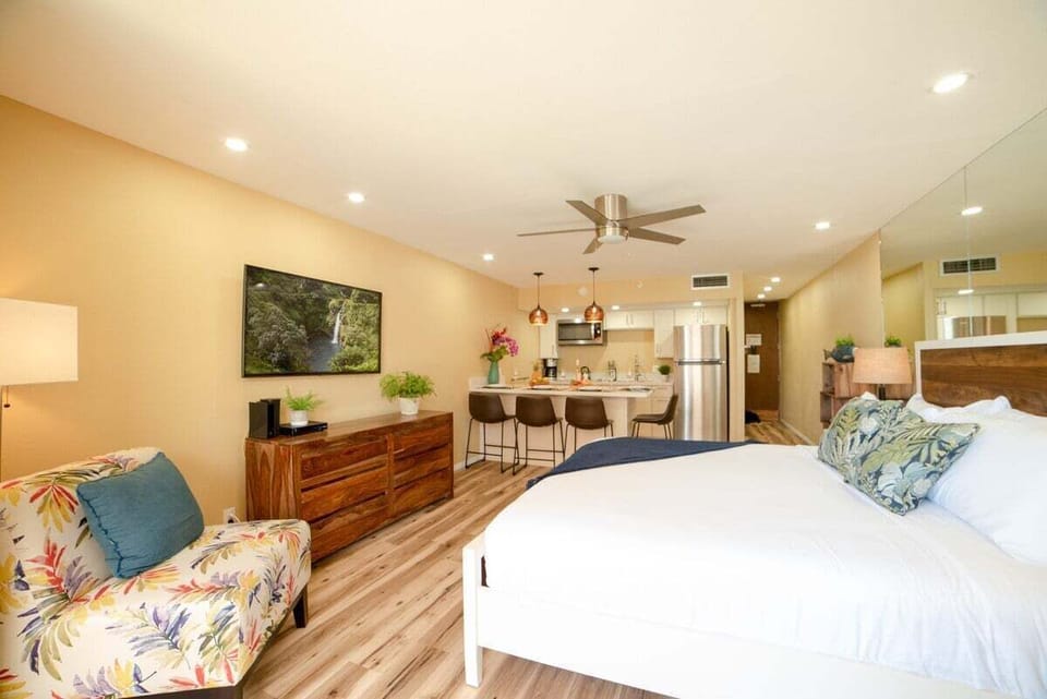 Alternate angle highlights floral armchair and cozy bed, with kitchen space flowing in the background.