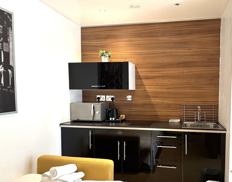 Kitchen equipped with microwave, coffee and tea kettle, mini fridge, and private space.