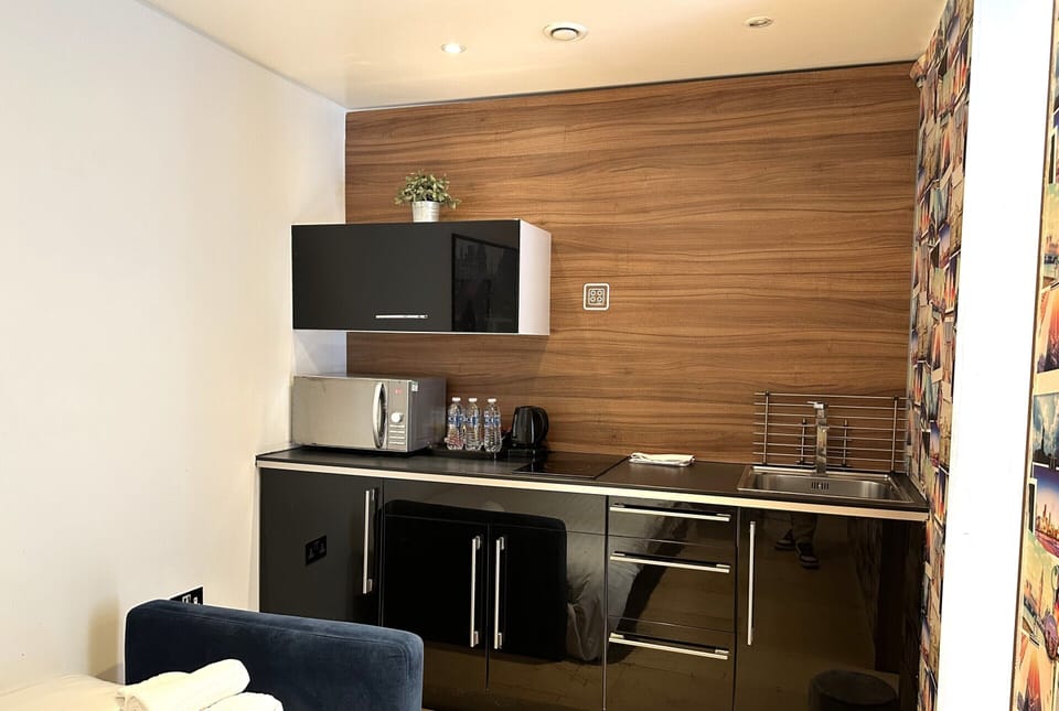 Kitchen equipped with microwave, coffee and tea kettle, mini fridge, and private space.