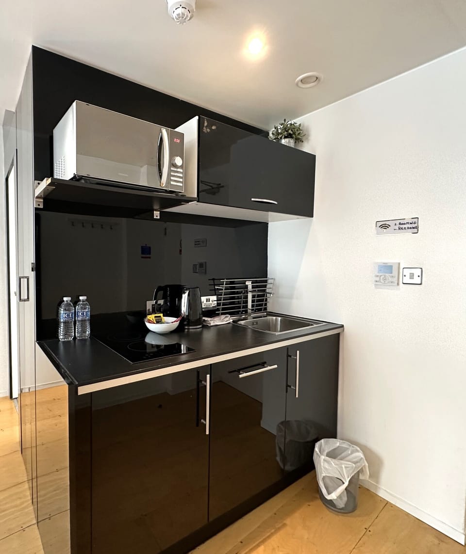 Kitchen equipped with microwave, coffee and tea kettle, mini fridge, and private space.