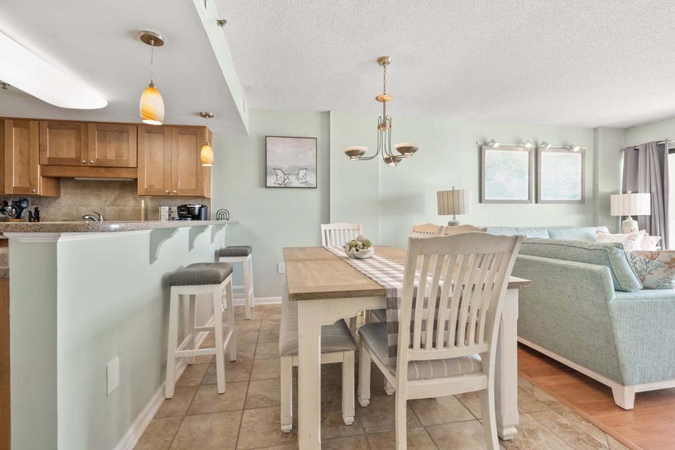 Kitchen island with bar stools beside the dining table at Crescent Towers II 707, Crescent Beach, North Myrtle Beach