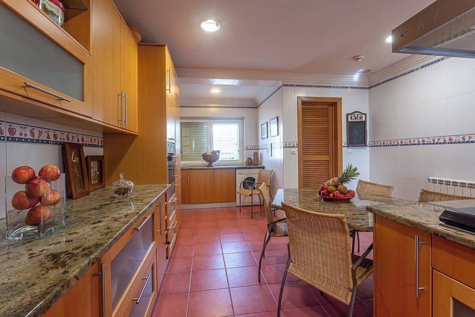 Spacious kitchen with granite countertops and wooden cabinetry — Villa Alegre, holiday villa in Seixal