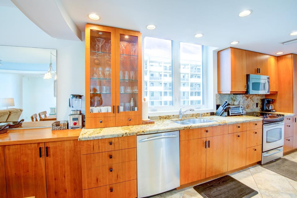 Kitchen with granite countertops, stainless steel appliances, glass-front cabinets, and tile flooring.