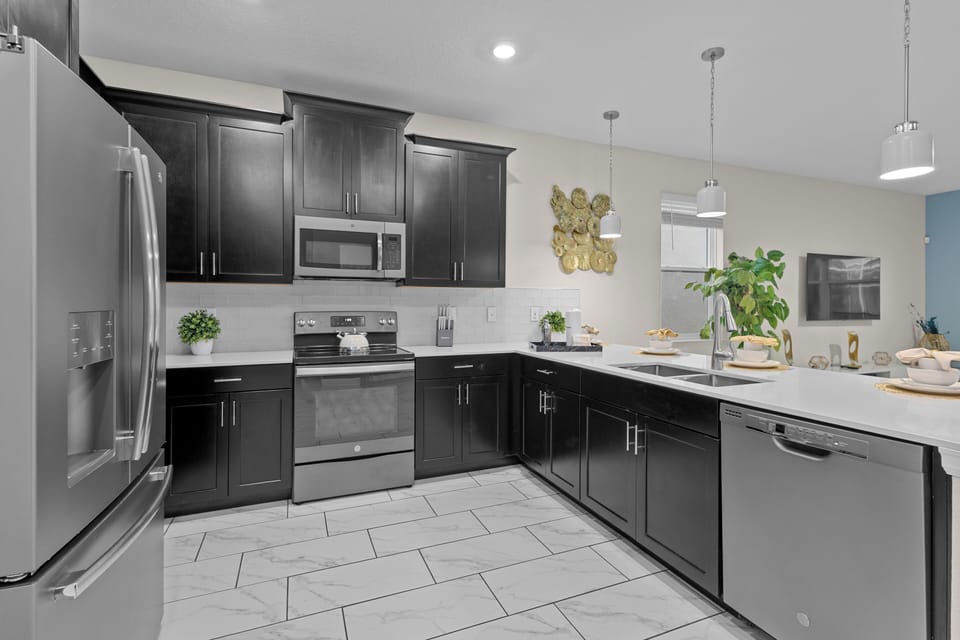 Cook memorable meals in this sleek modern kitchen featuring dark cabinetry, stainless steel appliances, and bright white countertops perfect for your culinary adventures.