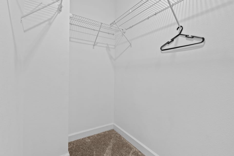 Your spacious walk-in closet offers ample hanging space with wire shelving and a hanging rod to keep your wardrobe organized during your stay.