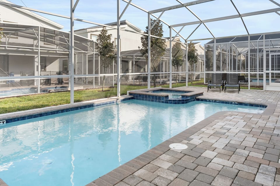 Your private screened pool and spa await, perfectly climate-controlled for year-round enjoyment with elegant paver decking.